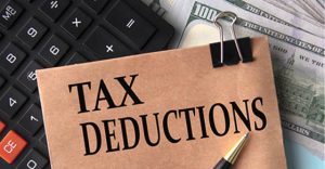 A file sitting with the words Tax Deductions on it sitting on a calculator